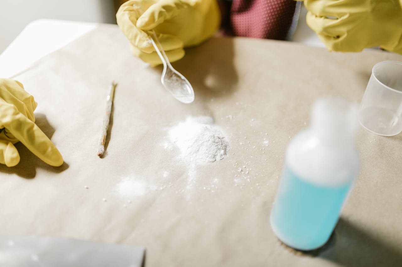 Close-up of a science experiment with yellow gloves, powder, and blue liquid indoors.